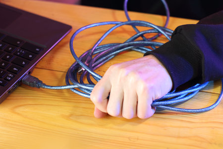 pulling with force the usb cable from the laptop on the table and colored background