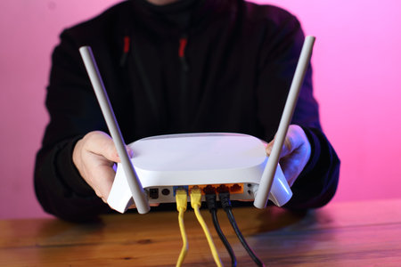 router with connected internet cables in the hands of a person over a table and a colored background