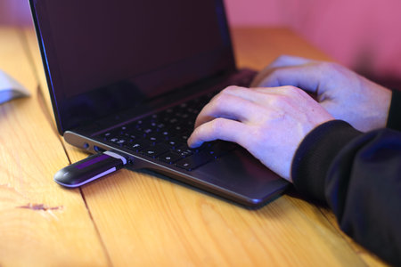 black gsm modem in a laptop against the background of a person typing on a keyboard in a black...