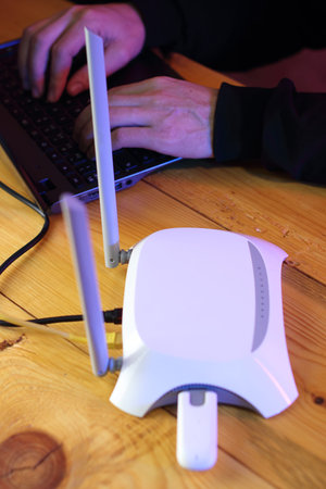 router with inserted gsm modem on table next to laptop and person typing