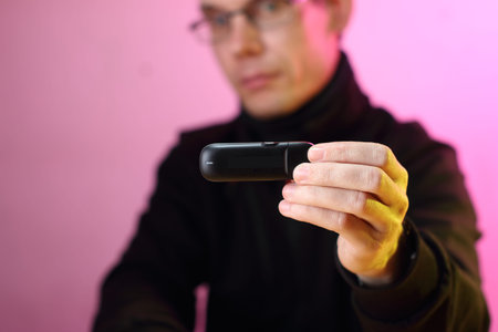 black gsm modem in the fingers of a person with a blurred background and a pink wall