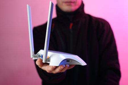 a person holding a white router with two antennas on a pink backgroundの写真素材