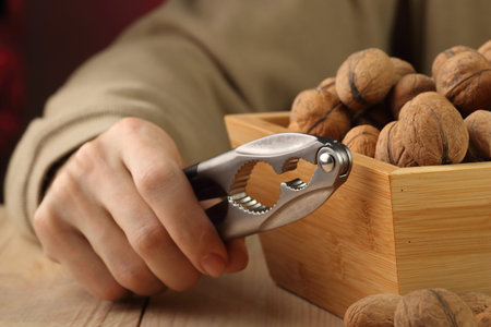 nutcracker held in hand next to a box of nuts