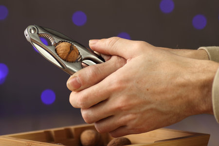 nutcracker clenched in hand with a walnut on a gray background