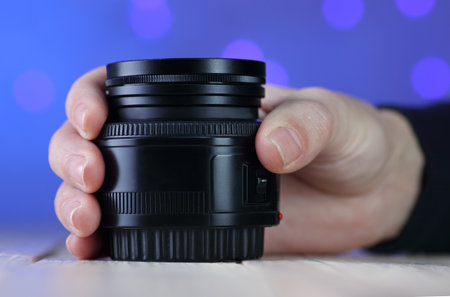 50mm lens in hand on table and colored backgroundの写真素材