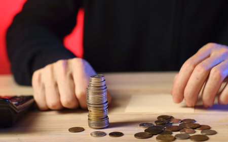 Hands of a young man counting coins on a wooden table.の写真素材