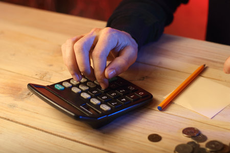 counting on a calculator by a person on a colored backgroundの写真素材