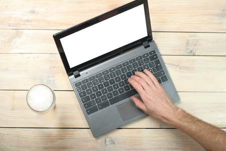 person typing on a laptop next to a beer mug on a wooden tableの写真素材