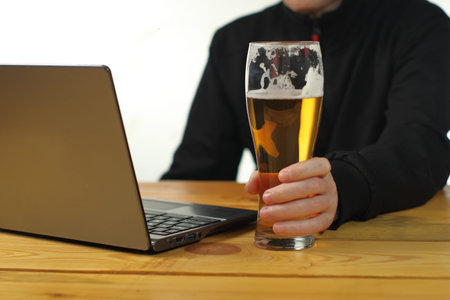 person holding a mug in front of a laptop on a wooden table