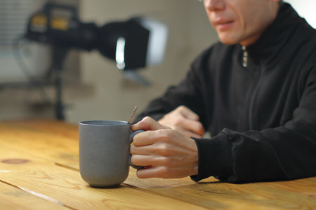 person holding a mug with coffee in front of him on the tableの写真素材