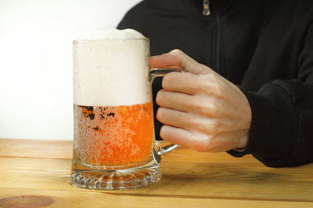 person holding a beer mug on the tableの写真素材