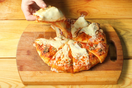 person takes a piece of pizza lying on the bottomの写真素材
