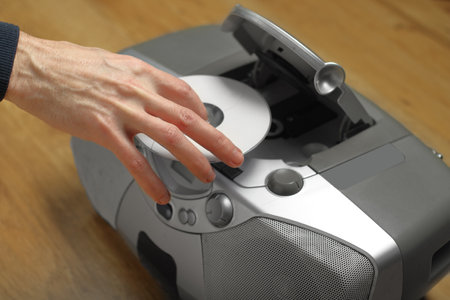 person puts compact disc into player on panel tableの写真素材