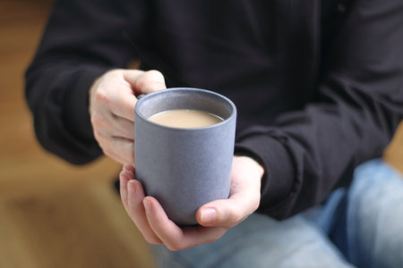 person holds a cup with coffee in his handsの写真素材