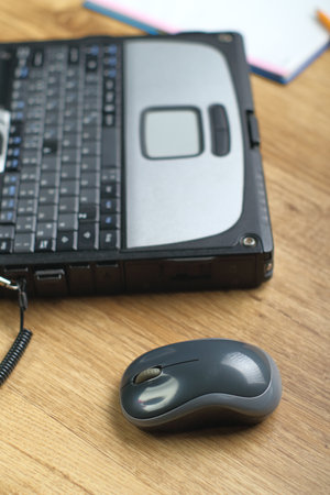 a computer mouse next to a laptop and a notebook in the background on the panelsの写真素材