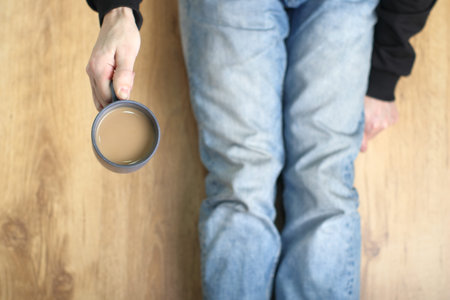 a person holding a cup with coffee on a paneled background