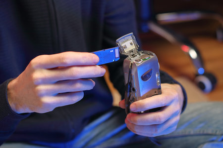 a person in the background taking out a memory card from an old compact camera