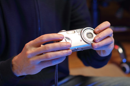 a person holds an old compact camera in his hands in front of him
