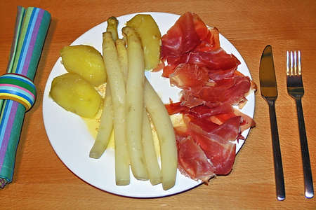 close up of asparagus, ham and potatoes, arranged on a white plate,の写真素材