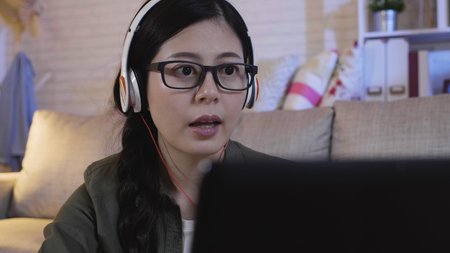 young girl wearing headphones and learning and talking with tutor online.