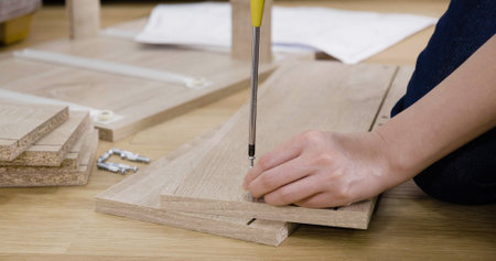 asian female assembling furniture in new house living room on wooden floor.