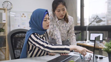 Ineffective office worker standing beside table and listening to irritated boss yelling