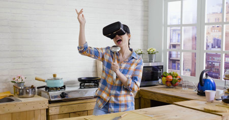 Attractive young funny asian japanese woman in virtual reality headset dancing and singing with...