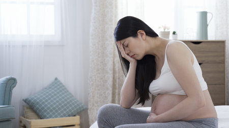 portrait of crying asian pregnant woman with bare belly expecting baby falling into a black...