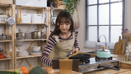 korean woman replaying the online cooking tutorial on tablet, trying to catch up. lady new to cooking finger dragging on time bar to rewind the video while stirring food in pan.の写真素材