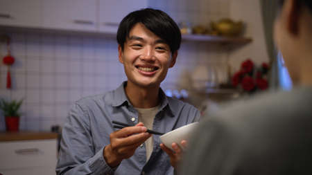 selective focus of a happy asian father talking and showing surprise while enjoying tasty reunion dinner with family on lunar new yearâs eveの写真素材