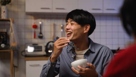 closeup with selective focus of a starved asian man father burning mouth on food and smiling with embarrassment while enjoying big meal on lunar new yearâs eveの写真素材