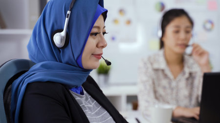 close up beautiful smiling Islamic service representative woman is wearing a headset and explaining with concentration.の写真素材