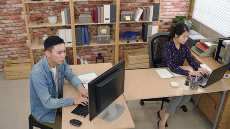top view asian creative team are consulting their smartphone and notes respectively while working on...