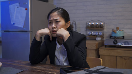 asian female employee being laid off is holding her head on the table and sighing in despair after...