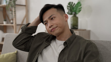 closeup shot of a worried asian male scratching head and looking at empty area with anxiety on the...