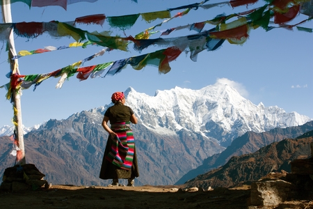 LANGTANG HIMAL NEPAL 18th OCTOBER 2010  Nepalese woman looking at Langtang peak and buddhist prayer flags Langtang Nepalのeditorial素材