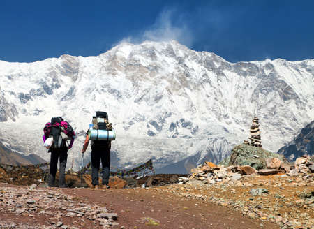View of Mount Annapurna with two tourists, round Annapurna circuit trekking trail, Annapurna south base camp, Nepal Himalayas mountainsの写真素材