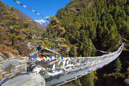 Rope hanging suspension bridge with prayer flags in Nepal Himalayas under Namche Bazar above Dudh Koshi Nadi river, Mount Everest base camp trekの写真素材