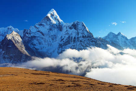 Mount Ama Dablam within clouds and blue sky, way to Mt Everest base camp, Khumbu valley, Sagarmatha national park, Everest area, Nepal Himalaya mountainの写真素材