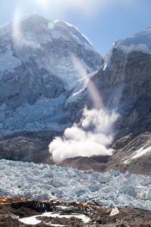 snow ice avalanche falling in sunshine from Mount Nuptse on Kumbu glacier to Everest base camp with yellow tents, Nepal Himalayas, mountain landscapeの写真素材