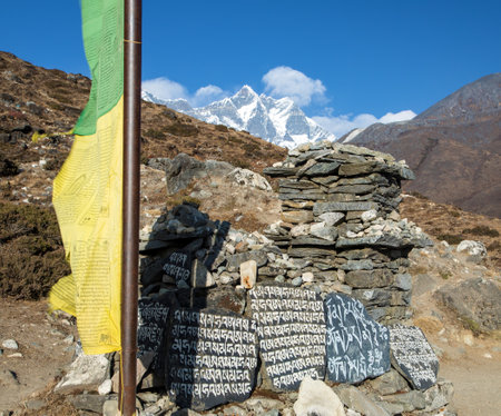Prayer flag and mani wall with buddhist symbols "Om Mani Padme Hum" and Lnotse peak, Khumbu valley, way to mount Everest base camp, Nepal Himalayas mountainsの写真素材