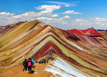Rainbow mountains or Vinicunca Montana de Siete Colores with tourists and beautiful clouds on sky, Cuzco region in Peru, Peruvian Andes, panoramic mountain viewの写真素材