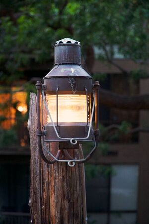 Retro lamp outdoors. Traditional street light, rusty and wooden outdoor decor. Vintage lighting with retro concept. Decorative metal object in a street.の写真素材