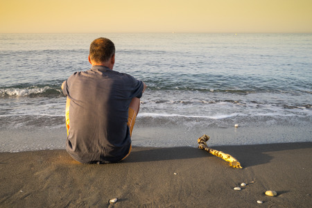 Lonely man on the beach in the sunsetの写真素材