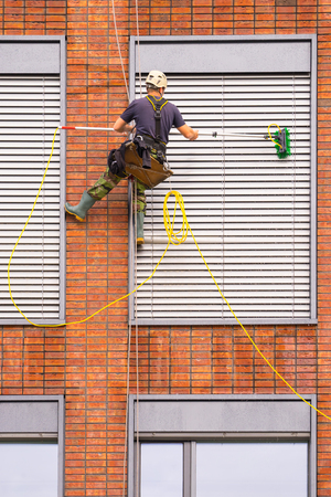 Cleaning windows, building facade with worker at height, man at workの写真素材