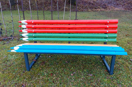 Bright multi-color design of street art design. White legs, which are attached by wooden beams in the form of colored pencils. Street bench, in the background a white carved fence.の写真素材