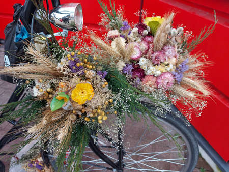 Red painted bicycle with a bucket of colorful flowersの写真素材