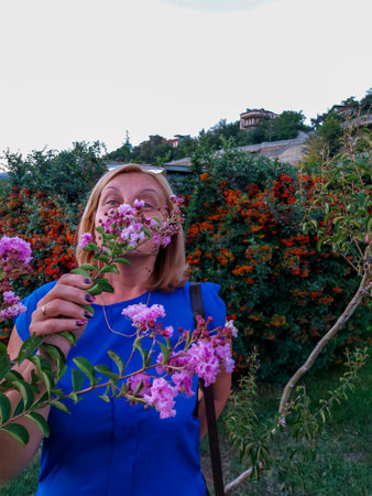Happy woman enjoying smell flowers over spring garden backgroundの写真素材