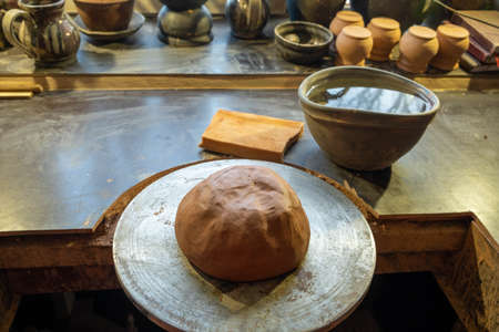 The clay lump on a potter's wheel waits for the potter to turn into wareの写真素材