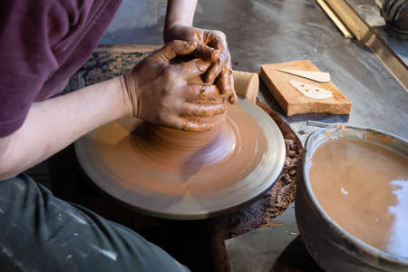 Hands of a potter at work. Potter making ceramic mug on the pottery wheel.の写真素材